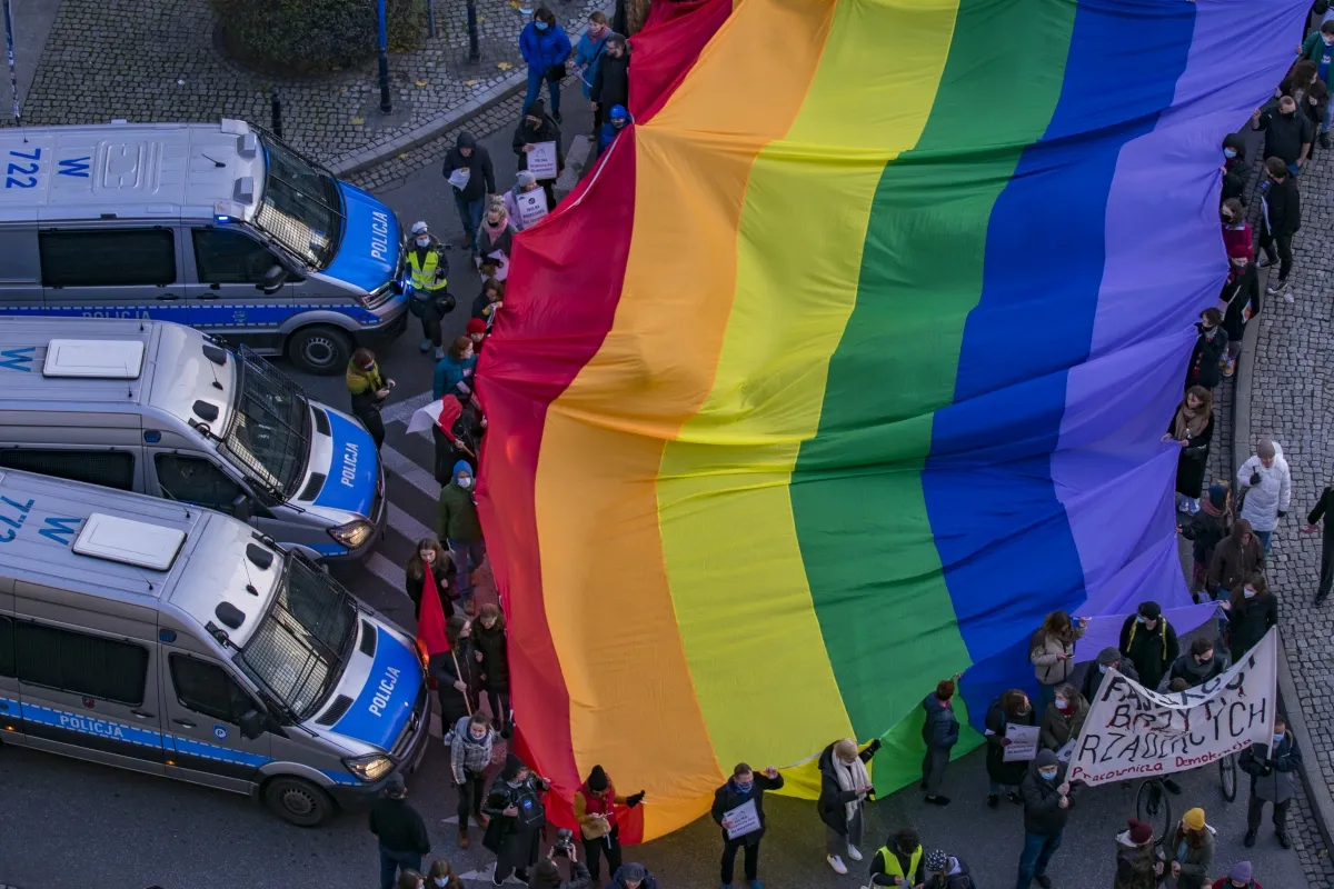 Giant rainbow flag stretched above police vans